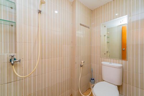 ein Bad mit einer Dusche, einem WC und einem Spiegel in der Unterkunft RedLiving Apartemen Cinere Resort - Gold Room in Gandul