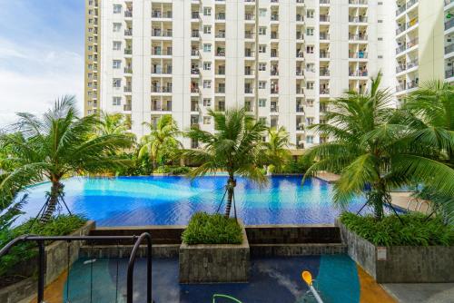 een groot gebouw met een groot zwembad met palmbomen bij RedLiving Apartemen Cinere Resort - Gold Room in Gandul