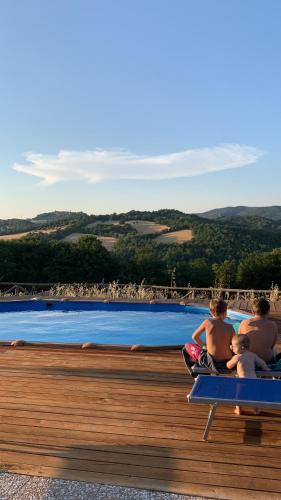 un grupo de tres hombres sentados en bancos junto a una piscina en Villa Cerciano, en Radicondoli
