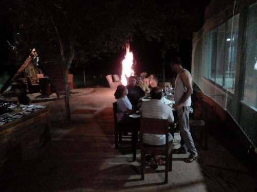 a group of people sitting at a table in front of a fire at Wilpattu Tree House in Wilpattu