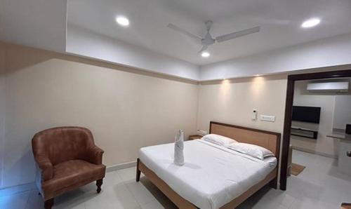 a bedroom with a bed and a chair at FabHotel Prime AM Suites Near Yashoda Hospital in Hyderabad