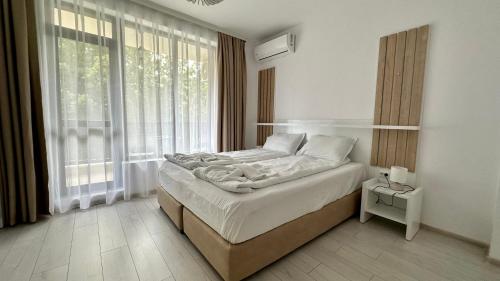 a bedroom with a bed and a large window at The Green Paradise Apartments in Primorsko