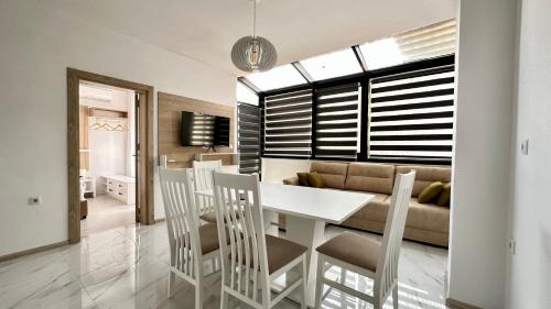 een eetkamer en een woonkamer met een witte tafel en stoelen bij The Green Paradise Apartments in Primorsko