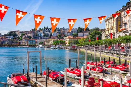 a bunch of boats are docked on a river with flags at Petit Cadeau - Happy Rentals in Cademario