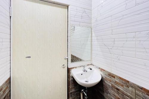 ein weißes Badezimmer mit einem Waschbecken und einem Spiegel in der Unterkunft RedDoorz At Damai Guest House Kabanjahe in Kabanjahe