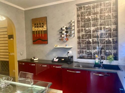 a kitchen with red cabinets and a wall with pictures at Ada’s Garden House in Rome