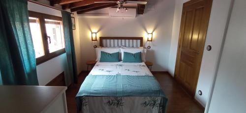 Un dormitorio con una cama con almohadas azules y una ventana en Buhardilla Ca'tio Celso, en San Esteban de la Sierra
