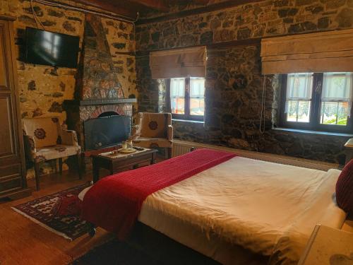 a bedroom with a bed and a tv and windows at Archontiko Tarsouna in Palaios Agios Athanasios