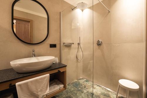 een badkamer met een wastafel en een douche met een spiegel bij Aparthotel Zum Schlössl in Villa Ottone