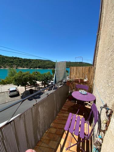 a balcony with a purple table and chairs and the ocean at balcon sur le lac in Bauduen