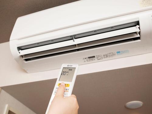 a person holding a remote control in front of a air conditioner at Hotel Route Inn Grand Chichibu in Chichibu