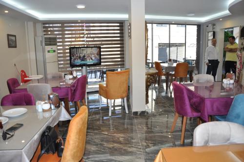 a restaurant with purple chairs and tables and a tv at Konak EuroBest Otel in Konak