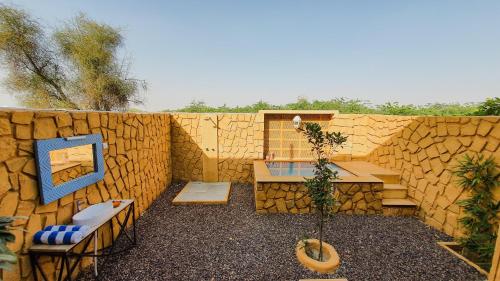 un patio trasero con una pared de piedra, una mesa y sillas en The Mama's Resort & Camp, en Kūri