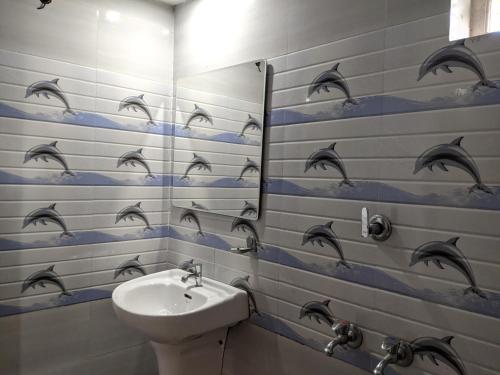 a bathroom with a sink and dolphins on the wall at Green View Executive Stay's in Ernakulam