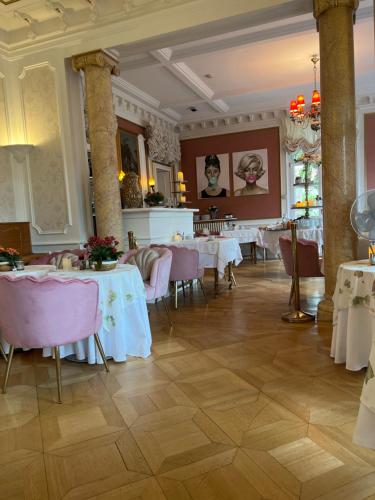 a restaurant with white tables and pink chairs at Hôtel Le Manoir in Barr