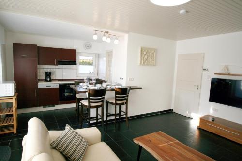 a living room with a couch and a kitchen with a table at Ferienhaus Pelikanstr 82 Ostermann Bungalow 3 in Norddeich