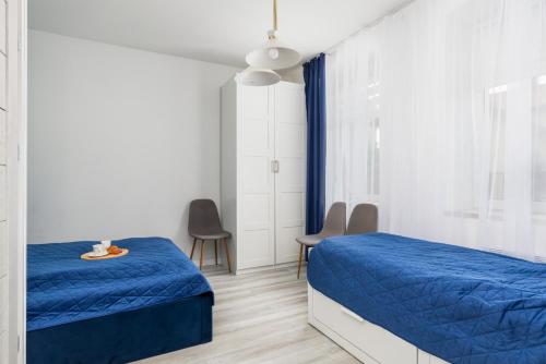a bedroom with two beds and a blue blanket at Apartament nad Jeziorem Kołczewo - Ogród & Parking by Renters in Kołczewo
