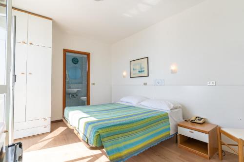 a white bedroom with a bed and a table at Hotel Concord in Lido di Savio