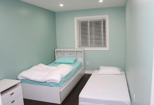 a blue room with two beds and a window at Quiet and Contemporary Home in Markham