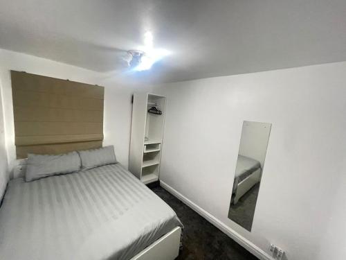 - une petite chambre avec un lit et un miroir dans l'établissement Femros Apartments, 15mins to city center., à Smethwick