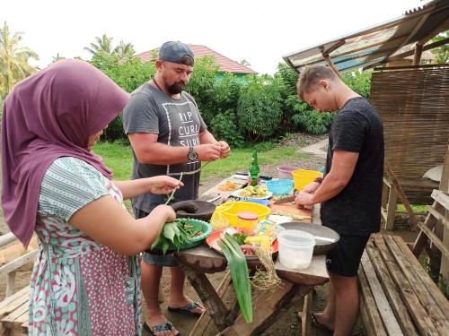 a group of people standing around a table preparing food at Bunga Maliq Bungalow Lombok in Tetebatu