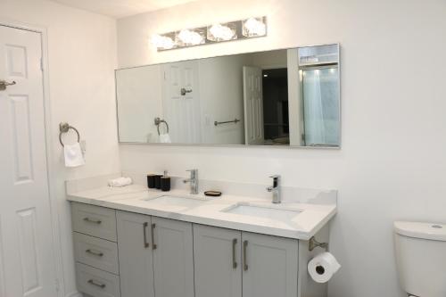 a white bathroom with a sink and a mirror at Quiet and Contemporary Home in Markham