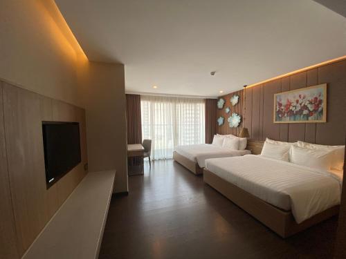 a hotel room with two beds and a flat screen tv at Virgo Hotel Nha Trang in Nha Trang