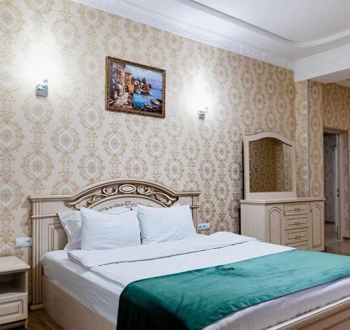 um quarto com uma cama grande e um cobertor verde em GRAND HOTEL SOGDIANA em Samarkand