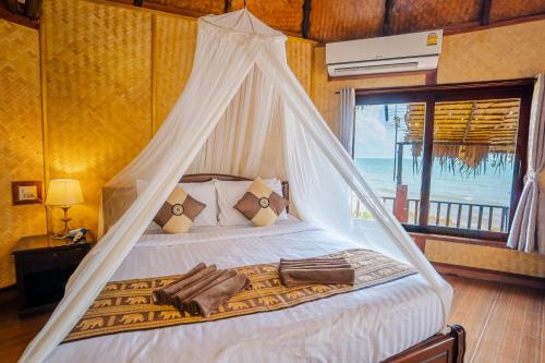 a bedroom with a canopy bed with a view of the ocean at Koh Jum Resort in Ko Jum