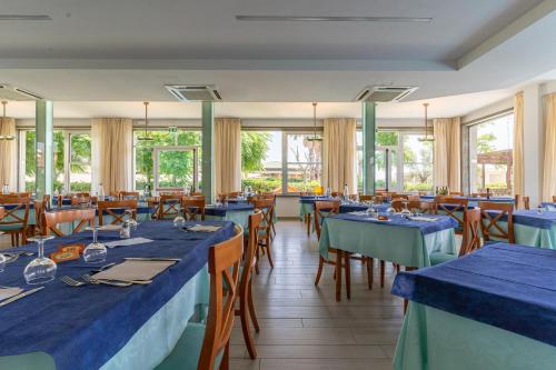 a restaurant with blue tables and chairs and windows at Hotel Concord in Lido di Savio