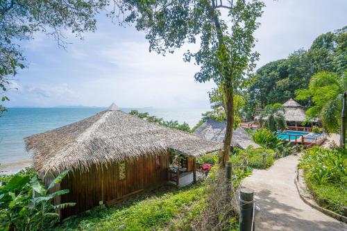 a small hut with a thatched roof next to the ocean at Koh Jum Resort in Ko Jum