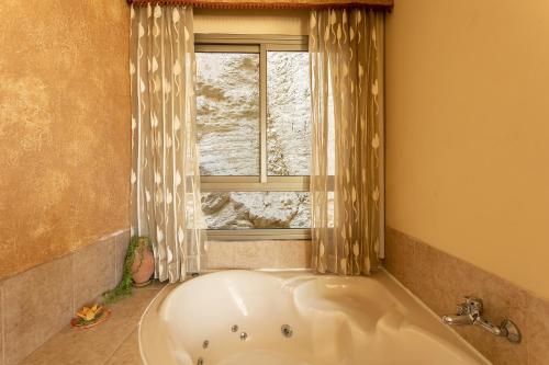 La salle de bains est pourvue d'une baignoire et d'une fenêtre. dans l'établissement Elmanzool Carmel Lodging, à ‘Isfiyā