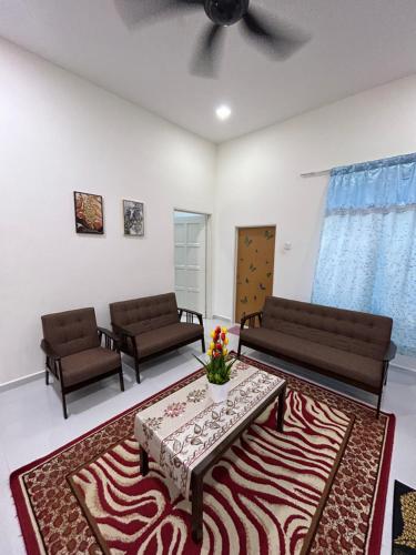 a living room with couches and a table and a rug at Teratak Cikgu Din in Marang