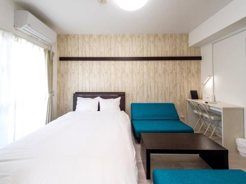 名護市にあるホテルトーマス名護のベッドルーム1室(ベッド1台、青い椅子2脚付)