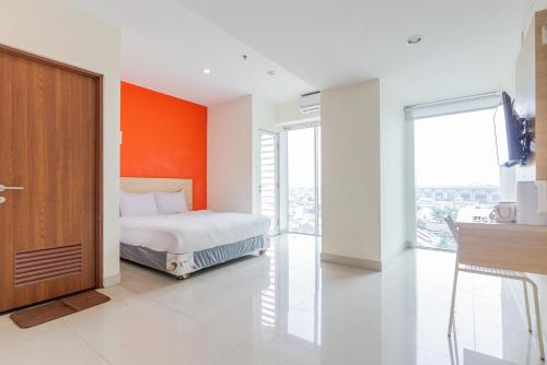 a bedroom with a bed with an orange wall at RedLiving Apartemen Grand Kamala Lagoon - Rooms 911 Tower Barclay South with Netflix in Bekasi
