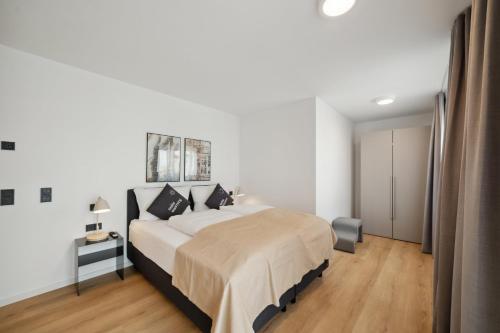 a white bedroom with a large bed and wooden floors at limehome Nuremberg Celtisplatz in Nuremberg