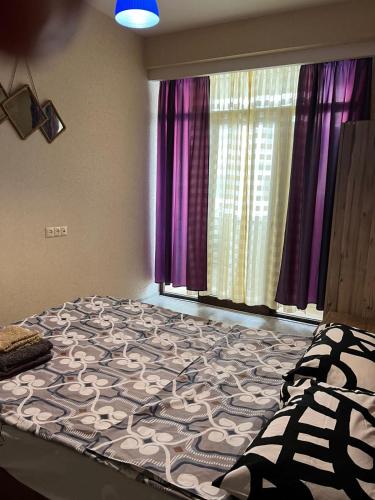 uma cama grande num quarto com cortinas roxas em Квартира в Диди Дигоми, Автандили N7 em Tbilisi