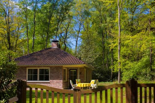 a small house with a wooden fence in front of it at Bungalowpark Bij de Bronnen in Nutter