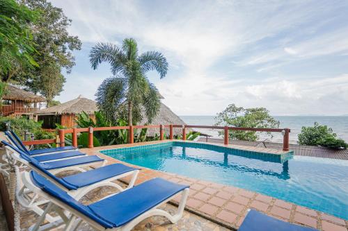 a pool with chairs and the ocean in the background at Koh Jum Resort in Ko Jum