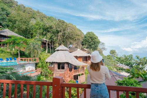 a woman standing on a fence looking at a resort at Koh Jum Resort in Ko Jum