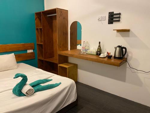 Una habitación con una toalla verde en una cama en Tavern Lodge Maafushi en Maafushi