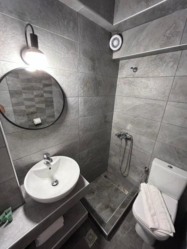 a bathroom with a sink and a toilet and a mirror at Studios Filio Sonia 2 in Vourvourou