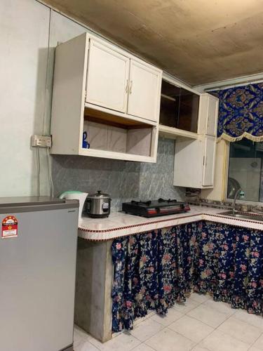 uma cozinha com armários brancos e uma bancada em GayaMas Homestay em Sandakan