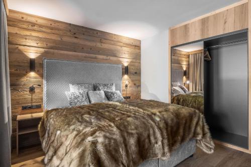 a bedroom with a large bed and a wooden wall at Lech Valley Lodge in Warth am Arlberg