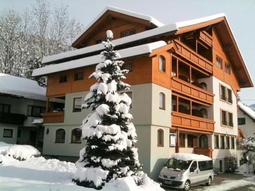a snow covered tree in front of a building at Familienhotel Steindl in Millstatt