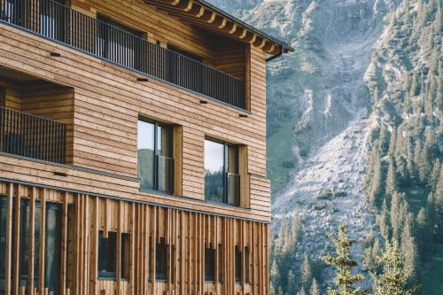 a wooden building with a mountain in the background at Lech Valley Lodge in Warth am Arlberg