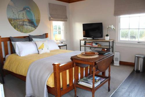 a bedroom with a bed with a television and a table at The Studio - Huntly House in Auckland