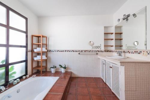 baño con bañera, 2 lavabos y ventana en Home2Book Villa El Naranjo, Garden & Pool, en Valsequillo