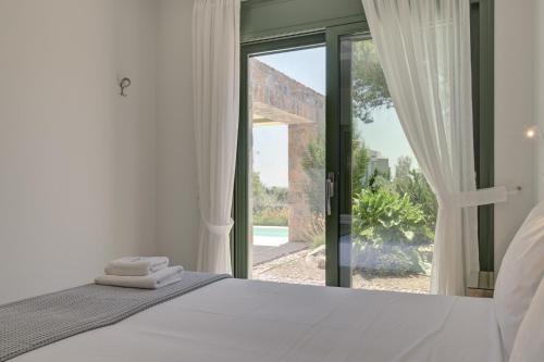 1 dormitorio con cama y ventana grande en Ouzo Stone House 1 with private pool, en Plomari