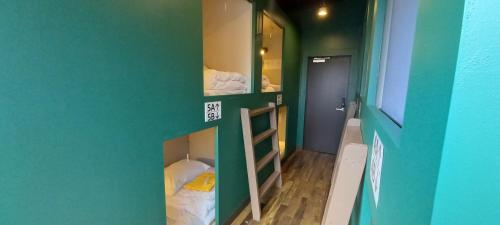Cette chambre comprend 2 lits superposés et un mur vert. dans l'établissement Wasabi Mita Hotel, à Tokyo